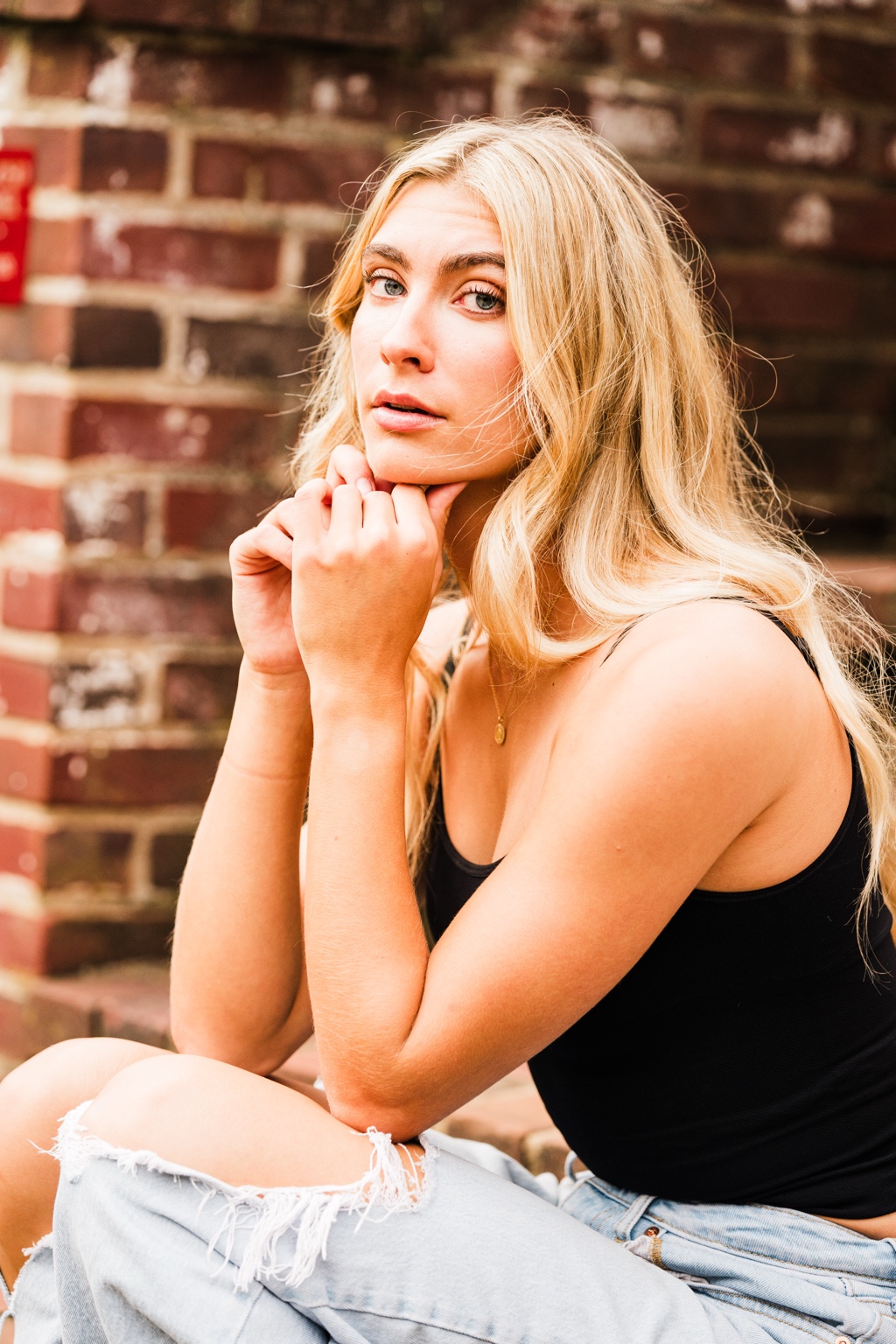 Cecilia seated by a brick wall